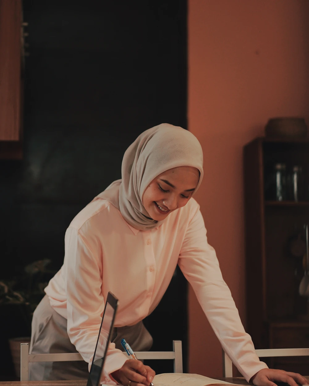 Femme voilée souriante, chez elle