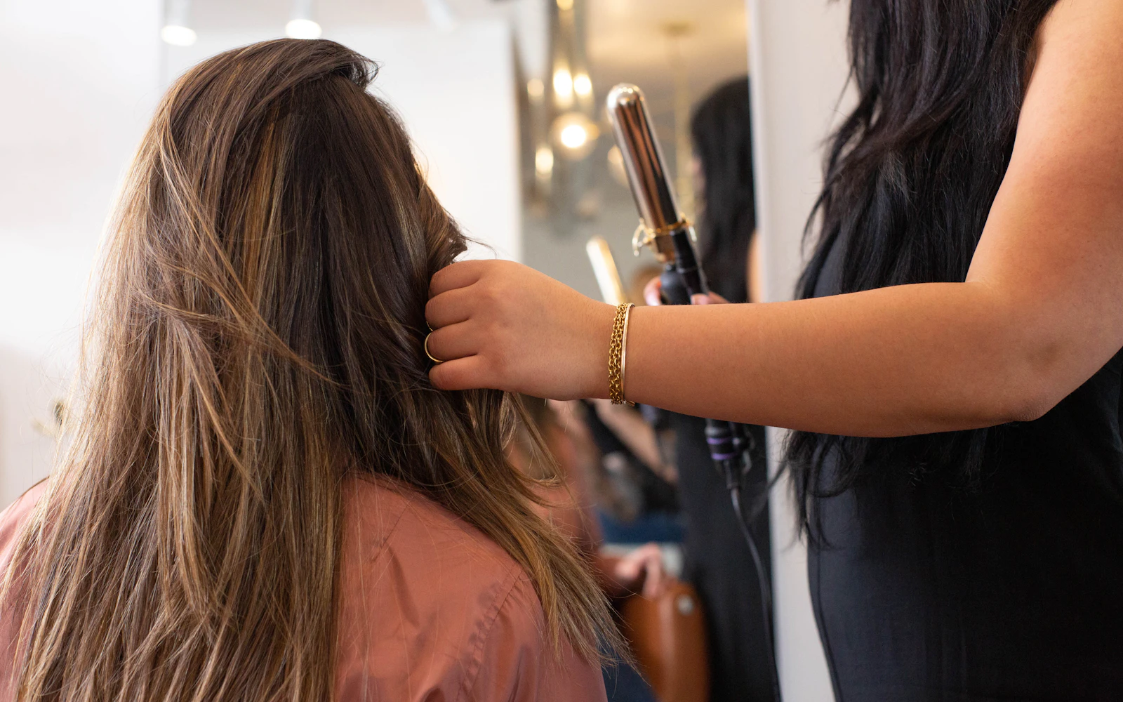 Une experte coiffe et lisse les cheveux d'une cliente en salon